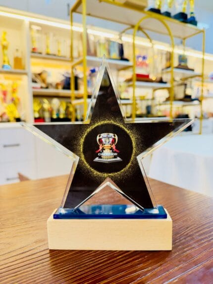 Custom five-point star crystal champion award with black and gold centre artwork and blue-tinted crystal base